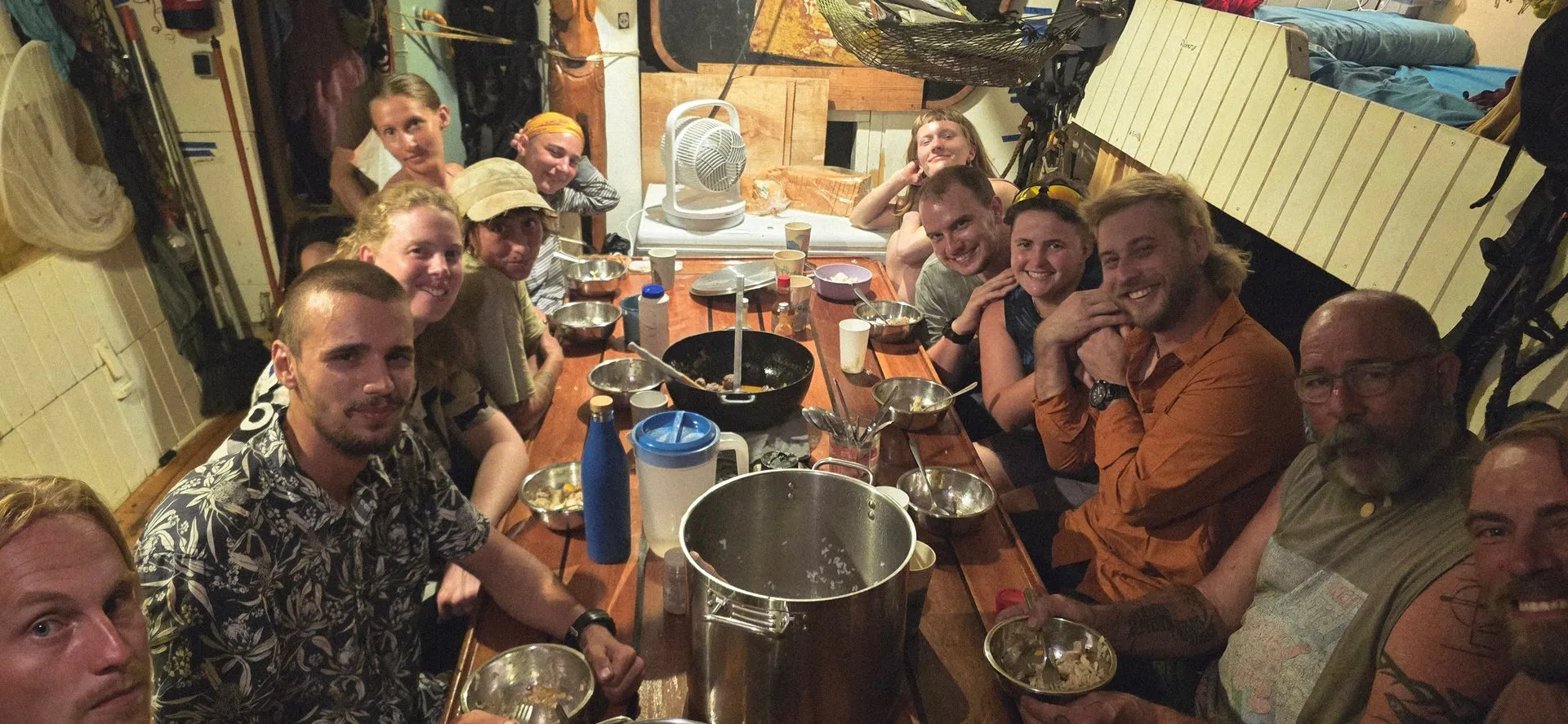 The whole crew gathered around the saloon table for dinner below deck