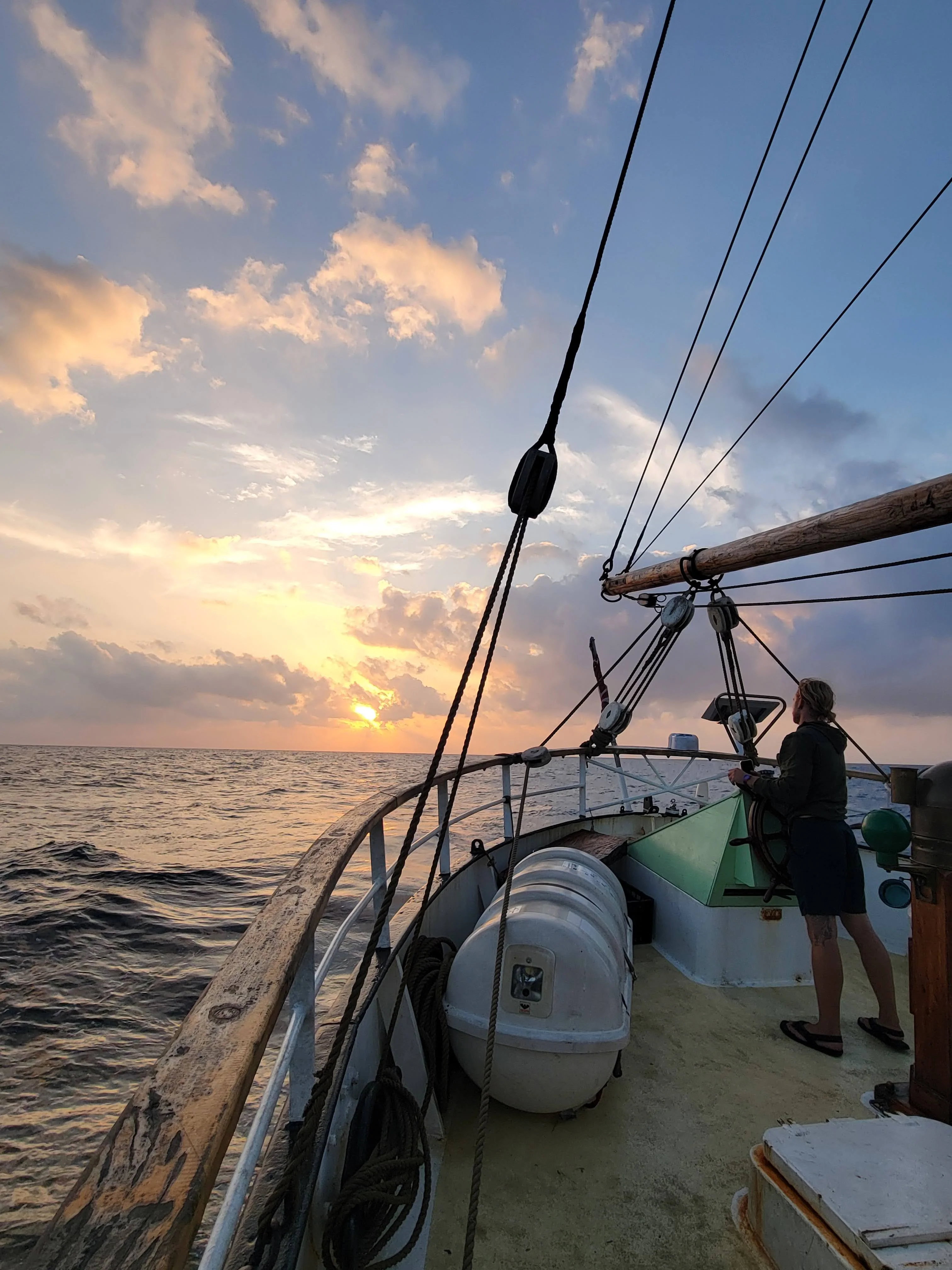 Helmsman steering Brigantine NEPTUN at sunset